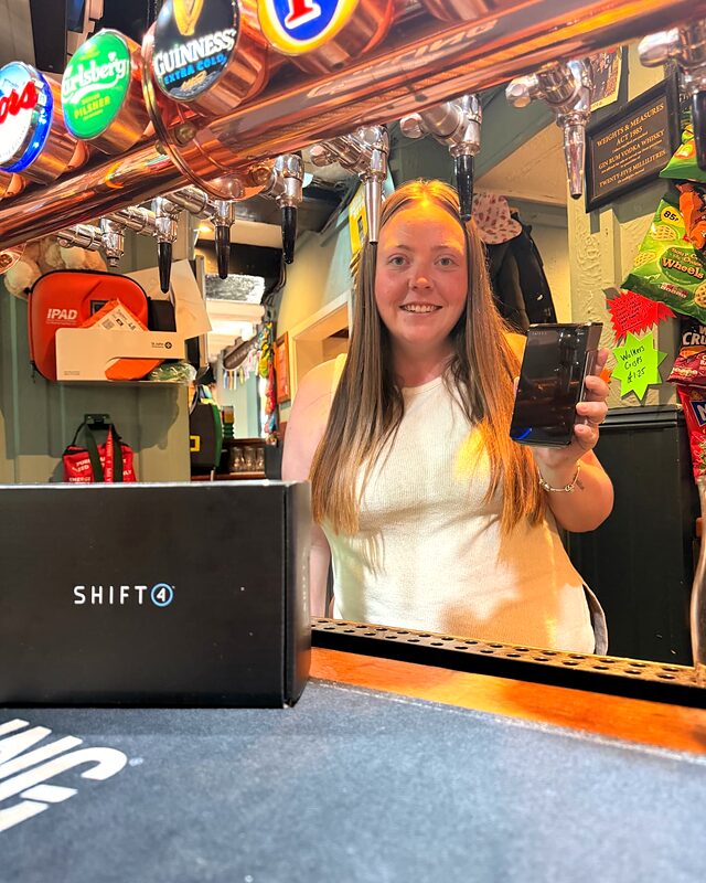 Bar staff at a village pub in Nottinghamshire holding a Shift4 card machine