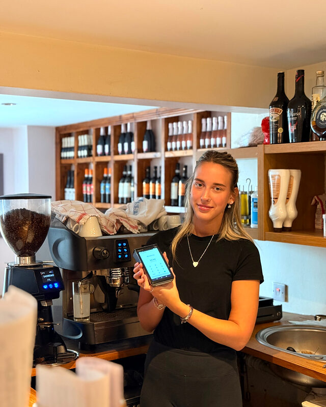 Barista in an independent Derbyshire café holding a Shift4 card machine